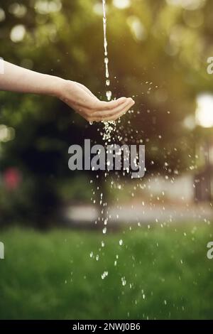 L'acqua è la vita, non la spreca. Scatto corto di acqua che corre su una mano di womans fuori. Foto Stock