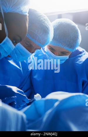 Focalizzato sulla procedura. Shot di gruppo di chirurghi che lavorano su un paziente in una sala operatoria. Foto Stock