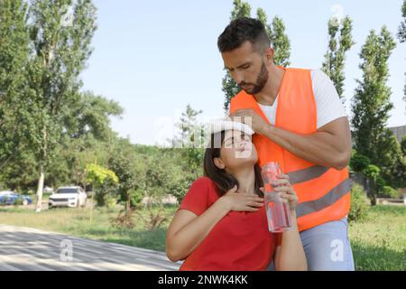 Lavoratore aiutare donna in città strada. Che soffre di colpo di calore Foto Stock