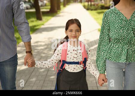 Genitori che prendono la loro figlia piccola a scuola all'aperto Foto Stock