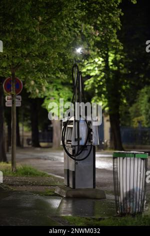 Stazione di servizio solitaria di notte vicino a un bidone dei rifiuti - grandi tettoie di alberi sopra di esso Foto Stock