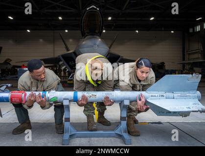 Un equipaggio di carico di 43rd Fighter Generation Squadron lavora insieme per sollevare un AIM-9 durante il concorso di carico di armi del 13 gennaio presso la base aeronautica Eglin, Flah. Due squadre hanno gareggiato per vedere chi poteva caricare un AIM-9 e un GBU-32 sul loro F-22 Raptor il più veloce e con il minor numero di errori. Il vincitore verrà annunciato durante la cerimonia di premiazione trimestrale dell'unità. Foto Stock