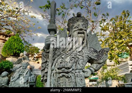 Statua in pietra di una storica figura cinese portata dalla Cina come zavorra sulle navi che consegnano riso, in un giardino a Wat Suthat, Bangkok, Thailandia Foto Stock