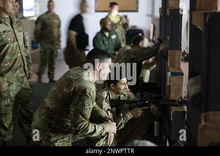 Una piccola coorte della Brigata Armorata del 15th, Kuwait Land Forces, guidata dal Colon. Al-Mekhyal, comandante, visita Camp Arifjan per praticare il tiro al Engagement Skills Trainer, un sistema simile a un videogioco per le abilità con le armi. Il col. Martin Wohlgemuth, comandante, Area Support Group - Kuwait, e il comando Sgt. Major Leon Black, NCOIC, ASG-KU, li ospitano spiegando il valore e il potenziale del sistema EST. Kuwait e soldati americani praticano la M9 pistola e il M4 fucile a Camp Arifjan, Kuwait, 26 gennaio 2023. Foto Stock