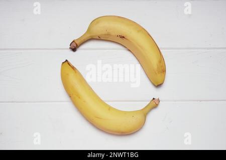 Due banane biologiche di formatura forma di cerchio su rustiche in legno bianco sullo sfondo Foto Stock