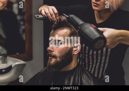 barber donna asciugando capelli cliente Foto Stock