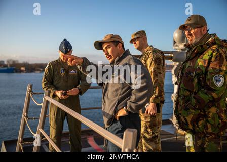 ROSTOCK, Germania (9 gennaio 2023) Lt. j.g. Dylan Cabrera, al centro, offre un tour del cacciatorpediniere missilistico guidato di classe Arleigh Burke USS Roosevelt (DDG 80) ai leader del Centro operativo per la difesa missilistica balistica della NATO Air Command; U.S. Air Force Lt. Col. Matthew Slusher, all'estrema sinistra, Stati Uniti Matthew Wright, a destra centrale, e Paesi Bassi Army Lt. Col. Derk Zielman, 9 gennaio 2023. Roosevelt è in fase di implementazione pianificata negli Stati Uniti Naval Forces Europe area of Operations, impiegato dagli Stati Uniti Sesta flotta per difendere gli interessi degli Stati Uniti, alleati e partner. Foto Stock