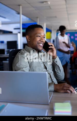 Donna d'affari afroamericana che parla su smartphone in ufficio. Lavorare in ufficio, business, finanza e concetto aziendale. Foto Stock