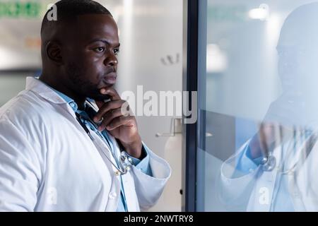 Medico afro-americano con stetoscopio pensando in ospedale. Concetto di salute, reparto ospedaliero e assistenza. Foto Stock