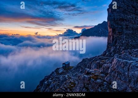 Vista dal Rifugio Tommaso Pedrotti sul Rifugio Tosa nelle Dolomiti di Brenta, valli ricoperte di nuvole, all'alba. Foto Stock