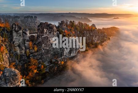 Sassonia, Germania - veduta aerea panoramica del Bastei in una mattina d'autunno nebbia con coloratissime foglie autunnali e nebbia pesante sotto la roccia. Bastei è un Foto Stock
