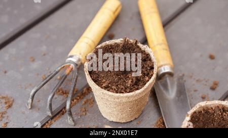 Primo piano di pentole per torba biodegradabili e utensili da giardino ecologici, vista dall'alto, messa a fuoco selettiva. Primavera giardinaggio naturale, eco, cura delle piante, biologico Foto Stock