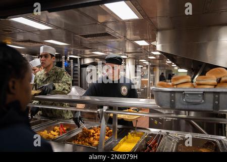 230203-N-CM110-1469 OCEANO PACIFICO (3 febbraio 2023) – Specialista culinario Seaman Lian Escobar, da Tampa, Florida, serve il pranzo all'equipaggio e ai loro amici e familiari durante la crociera di un giorno con amici e familiari a bordo di un carrier d'assalto anfibio USS Tripoli (LHA 7) 3 febbraio 2023. Tripoli ospita più di 500 familiari e amici per dimostrare le capacità della nave. Tripoli è una nave d'assalto anfibio di classe americana ospita a San Diego. Foto Stock