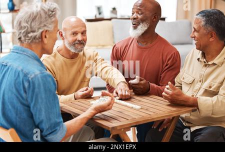 Uomini anziani, amici e domino in giochi da tavolo su tavolo di legno per attività, legame sociale o riunione. Gruppo anziano di giocatori di domino che si divertono Foto Stock