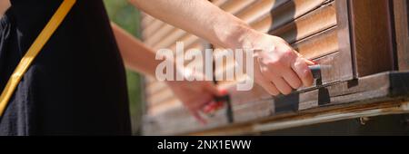 Le mani femminili tengono le maniglie del fermo di legno aprono le tende di legno all'aperto closeup. Concetto di apertura della tendina parasole a rullo Foto Stock