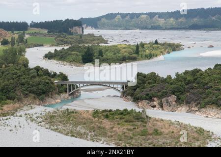 Un'ampia vista panoramica del fiume Rakaia a bassi livelli d'acqua e un ponte su di esso in Nuova Zelanda. Foto Stock