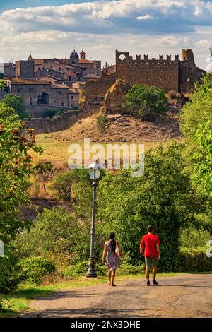 I turisti visitano l'antica città di Tuscania, sullo sfondo i ruderi del Castello Rivellino. Toscana, provincia di Viterbo, Lazio, Italia, Europa Foto Stock