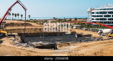 Pompa per calcestruzzo che lavora su fondazioni rinforzate in un cantiere di grandi dimensioni Foto Stock