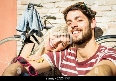 Felice coppia hipster che prende selfie al viaggio della città vecchia con la bicicletta d'epoca - concetto di divertimento con i viaggiatori di città di moda alternativa - bel ragazzo wi Foto Stock