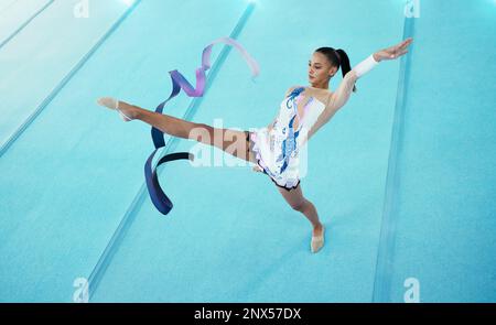 Ginnastica, donna ballare con nastro e prestazioni, flessibilità con atleta professionista in palestra e vista dall'alto. Ginnastica ritmica, gamba in aria con Foto Stock