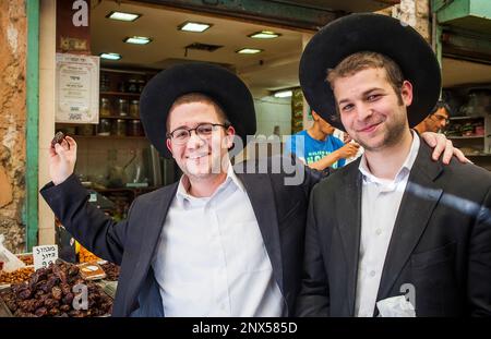 Amici, mostra una data, gli Ebrei Ortodossi, in Mahane Yehuda Market, Gerusalemme, Israele. Foto Stock