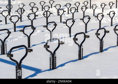 Portabiciclette in metallo nero. La foto è stata scattata in una giornata invernale di sole. Rack proietta ombre nella neve. Foto Stock