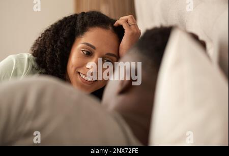 Giovane coppia multirazziale sorridente che parla insieme a letto Foto Stock