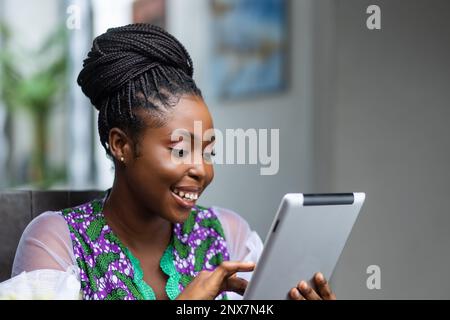 Young African Woman Shopping online con tablet, mobile banking, effettuare prenotazioni online a casa. Foto Stock