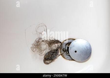 Lo scarico della doccia è ostruito con i capelli, perdita del pelo dei capelli in un bagno dopo il lavaggio dei capelli nella doccia, pulizia del bagno e rimozione della vista superiore dei capelli Foto Stock