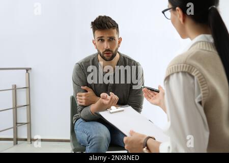 Psicoterapeuta che lavora con l'uomo tossicodipendente al chiuso Foto Stock