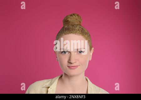 Giovane donna tintura i capelli con henné su sfondo rosa Foto Stock