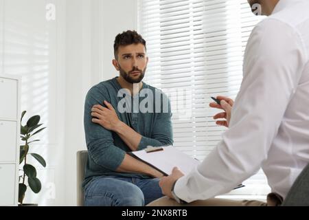 Psicoterapeuta che lavora con l'uomo tossicodipendente al chiuso Foto Stock