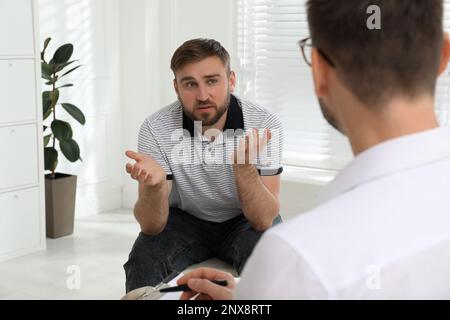 Psicoterapeuta che lavora con un giovane tossicodipendente al chiuso Foto Stock