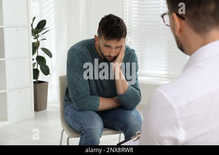 Psicoterapeuta che lavora con l'uomo tossicodipendente al chiuso Foto Stock