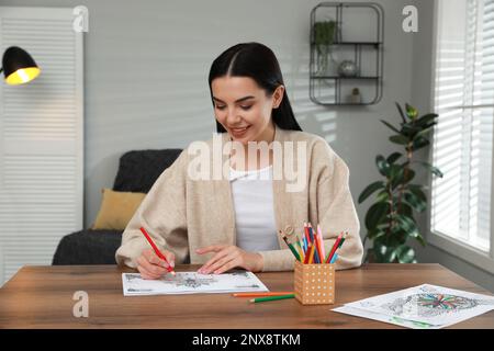Giovane donna colorazione antistress pagina a tavola in interni Foto Stock