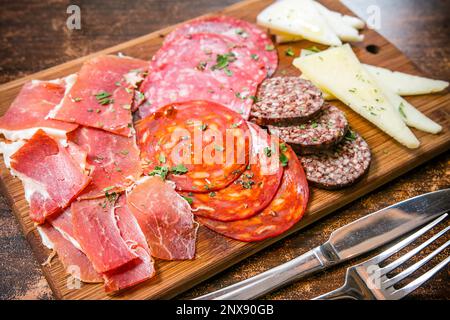 Cucina italiana - un pannello di legno con salumi assortiti e formaggi gourmet, tra cui prosciutto di Parma, salumi e chorizo. Foto Stock