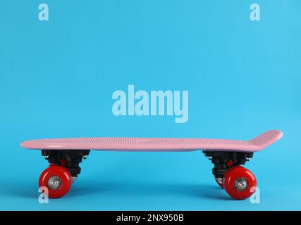 Skateboard rosa su sfondo azzurro. Spazio per il testo Foto Stock