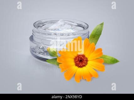 Gel trasparente con estratto di calendula su fondo grigio chiaro. Prodotto cosmetico a base naturale Foto Stock