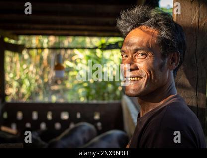 Un uomo in un villaggio rurale nella provincia di Siem Reap, in Cambogia, si trova accanto a una stettissima azienda di suini giovani. Foto Stock