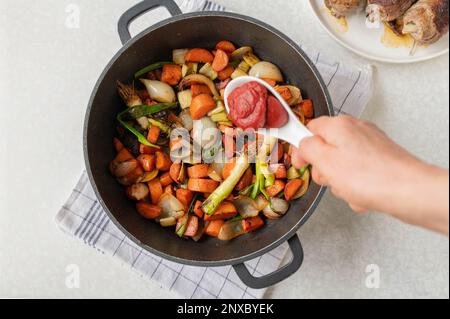 Mettere la pasta di pomodoro in una padella con verdure tritate e arrostite per preparare la salsa o il sugo. Parte di una serie cottura, preparazione, preparazione Foto Stock