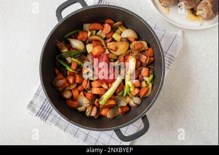 Verdure di radice arrosto o mirepoix con pasta di pomodoro in una teglia per la cottura di salsa per involtini di manzo. Parte di una serie Foto Stock