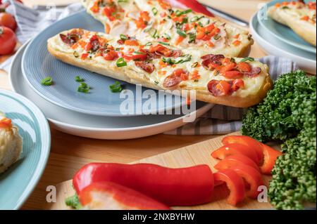 Bistrot baguette sandwich con salame, prosciutto, formaggio, peperoni rossi e erba cipollina. Cucinato in casa Foto Stock