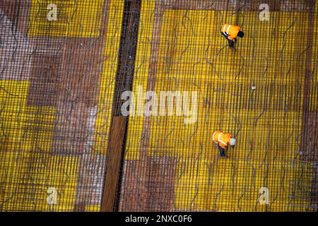 Vista dall'alto dei lavoratori che preparano una piastra di fondazione in cemento in un cantiere. Foto Stock