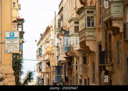 Valletta, Malta - 12 novembre 2022: Facciate residenziali in pietra calcarea intemperate con tradizionali balconi in legno nella capitale di Malta Foto Stock