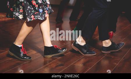 Scarpe da ballo di giovani coppie ballano balli jazz swing retrò su un locale da ballo con pavimento in legno, vista ravvicinata di una scarpa, femminile e maschile, lezioni di danza Foto Stock