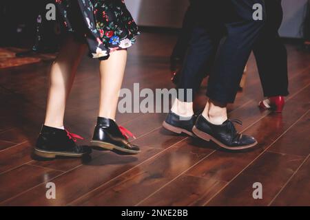 Scarpe da ballo di giovani coppie ballano balli jazz swing retrò su un locale da ballo con pavimento in legno, vista ravvicinata di una scarpa, femminile e maschile, lezioni di danza Foto Stock