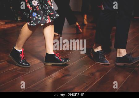 Scarpe da ballo di giovani coppie ballano balli jazz swing retrò su un locale da ballo con pavimento in legno, vista ravvicinata di una scarpa, femminile e maschile, lezioni di danza Foto Stock