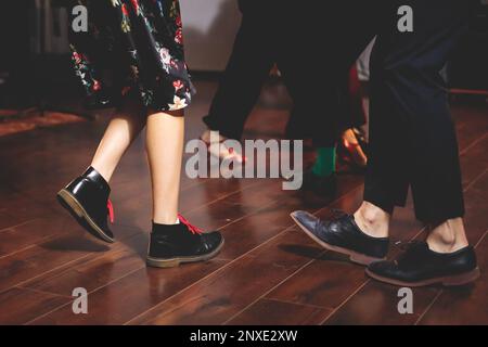 Scarpe da ballo di giovani coppie ballano balli jazz swing retrò su un locale da ballo con pavimento in legno, vista ravvicinata di una scarpa, femminile e maschile, lezioni di danza Foto Stock