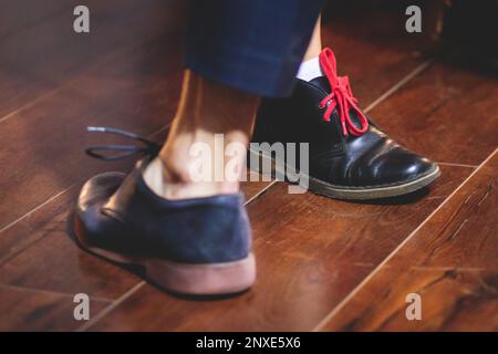 Scarpe da ballo di giovani coppie ballano balli jazz swing retrò su un locale da ballo con pavimento in legno, vista ravvicinata di una scarpa, femminile e maschile, lezioni di danza Foto Stock