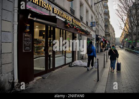 Persona senza casa che dorme fuori una panetteria al mattino. Parigi Francia Foto Stock